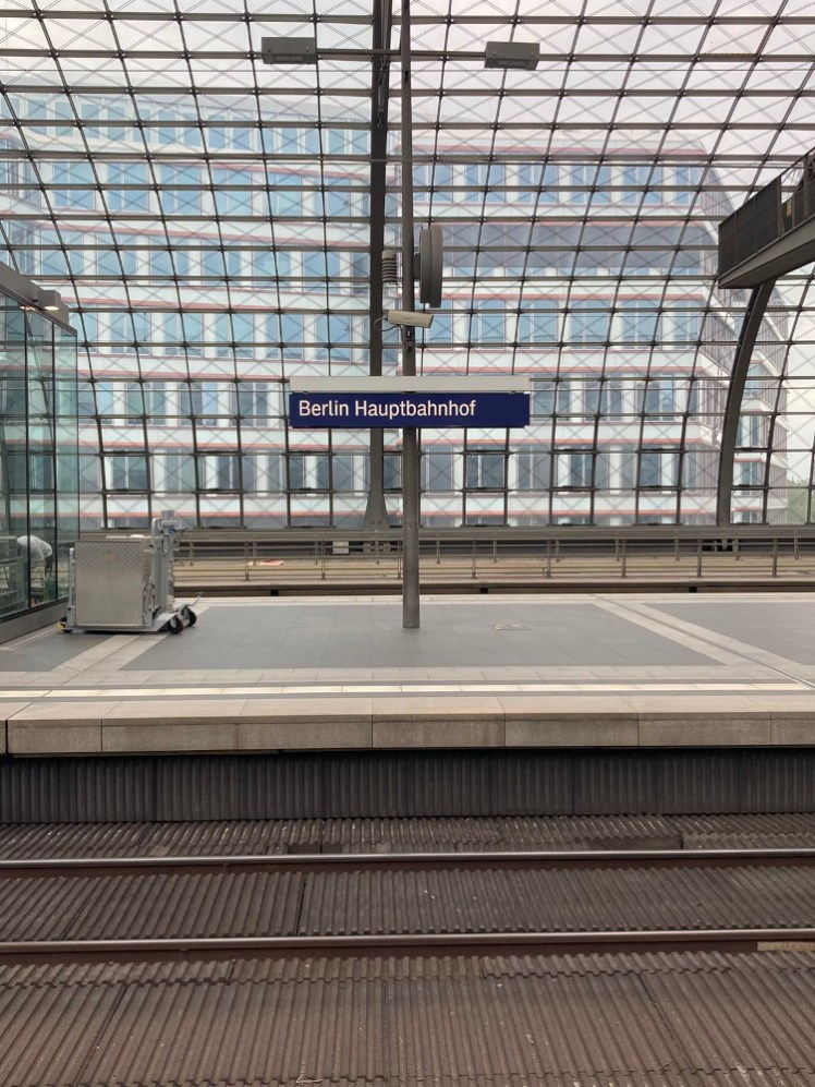 A sign for Berlin Hauptbahnhof against the curved iron and glass roof of the station.