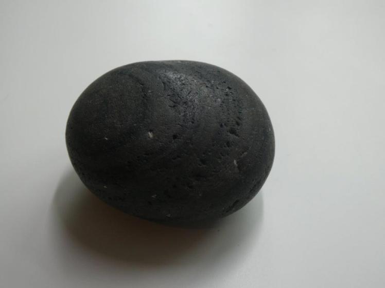 A perfect oval-shaped sea-rounded black pebble