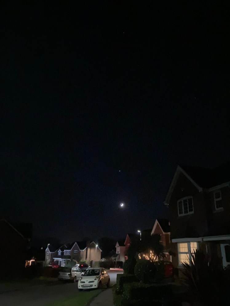 Waxing crescent moon over a residential street. Just above the moon you can see Jupiter.