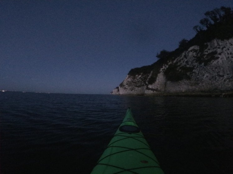 A night kayak adventure. You can see the chalk cliffs fairly well by the dim twilight and you can make out a bright green sea kayak stretching out in front of me.