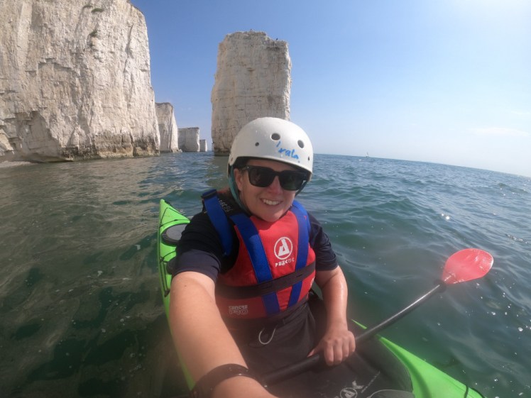 Me in a sea kayak out on the open sea, with chalk stacks, stumps and features worthy of a geography textbook behind me.