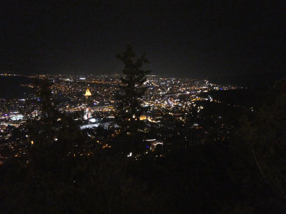 Tbilisi by night from the funi. The city lights go on forever but a very prominent one is a big golden church in the middle, the Holy Trinity Cathedral.