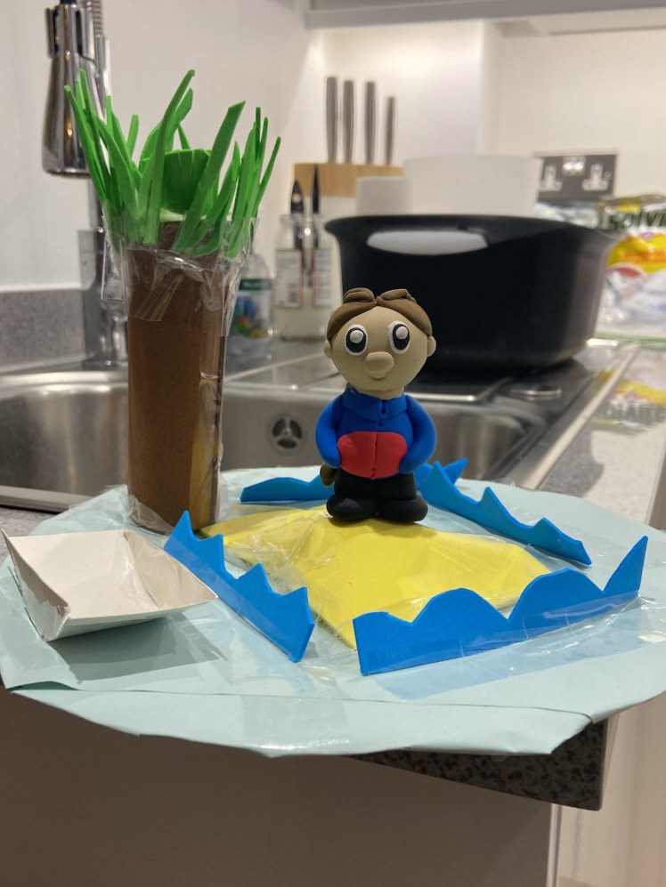 A Guide mini me on a hand-crafted desert island with unusually thick palm tree. It appears to be balanced right on the edge of a kitchen sink.