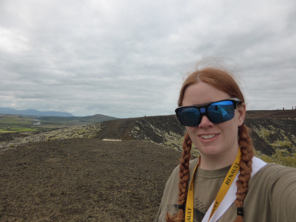 Me in 2014, with reddish hair and a grey-green t-shirt that almost blends into the damp weather and volcano, on top of Big Grábrók. I've got my car keys on a yellow Renault lanyard round my neck and the white strap of my day bag across my shoulder. Please ignore the gigantic square blue mirrored sunglasses that I should never have bought.