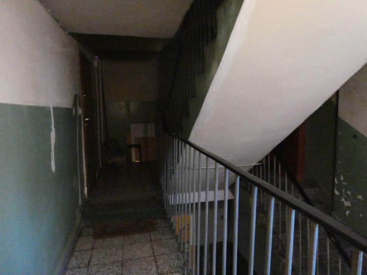 Inside the apartment, outside my door. It's dark and there are staircases going in every direction.