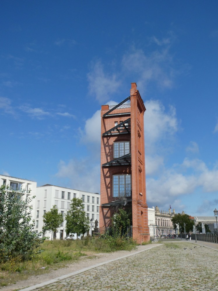 The remains of Bauakademie, two sides of a brick tower, its two sides held together by metal bars.