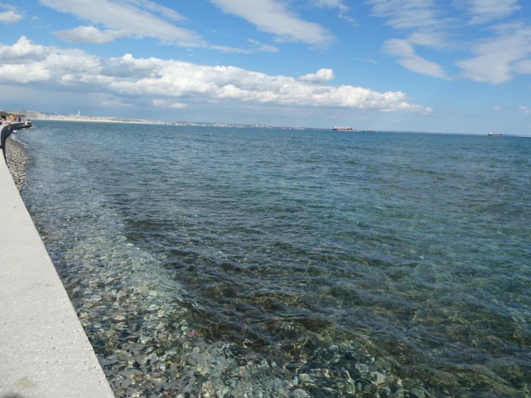 A view along the very edge of the prom, showing the shallow and very clear, very blue Mediterranean, sparkling in the sun.