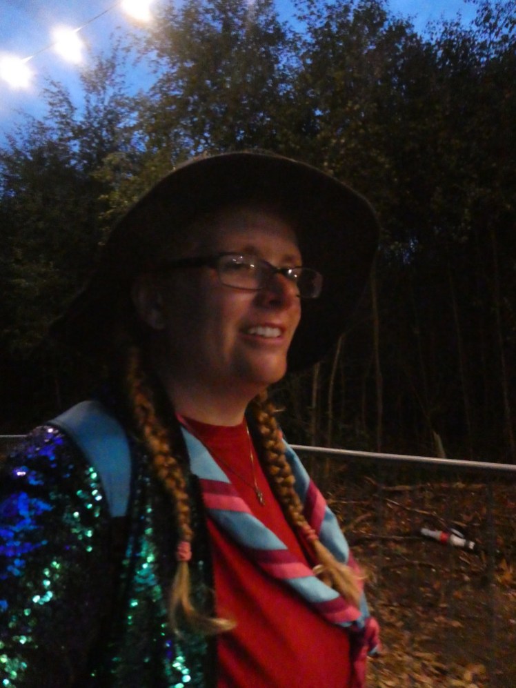 A selfie on Friday night. I'm wearing a kind of knitted black witch's hat, a red t-shirt, a neckerchief in turquoise with bright pink and purple borders - oh, and a blue-green sequin bomber jacket.