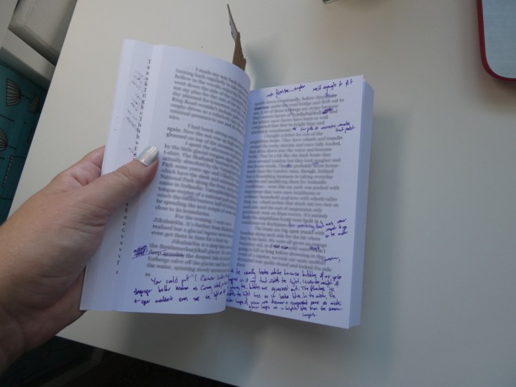 The first draft of my second book, open to a page with a lot of purple scribblings and corrections. The actual text is blurred because it's too bad for