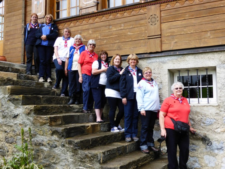 We weren't backpacking but a group photo of a trip to Switzerland in which I was the second-youngest at 28, with 7 out of 10 of us being in their 60s, 70s and 80s. We're all standing on the stone steps at the back of a traditional Swiss chalet, in various kinds of Guiding uniform, mostly in shades of blue, white and red.
