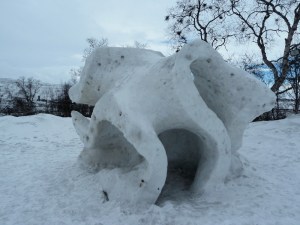 An abstract vaguely cubic snow sculpture with sharp swirls instead of straight edges.