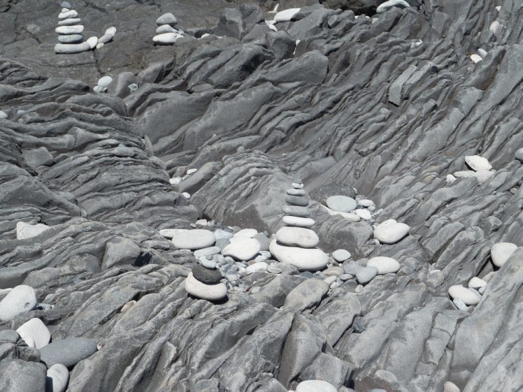 Stacks of rocks left lying on an interesting bit of cliff that's been folded and cracked and folded again and has now curved to become as much beach as cliff.