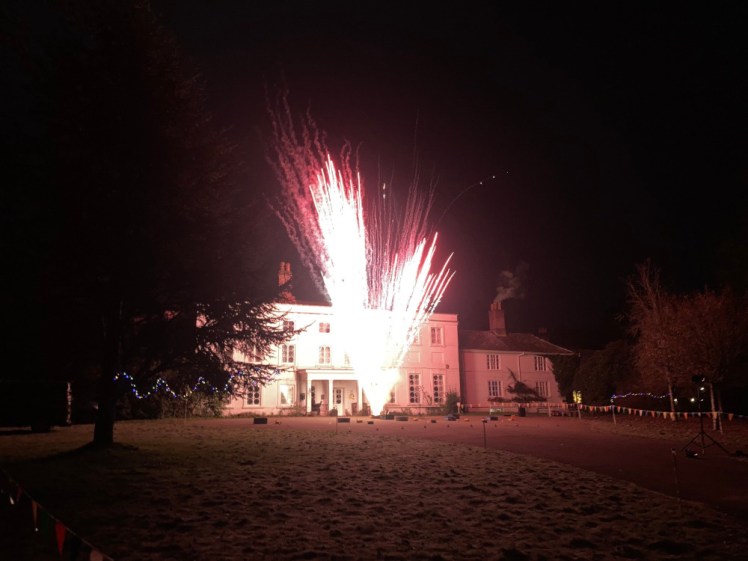 Red fireworks spraying up from outside the main house.