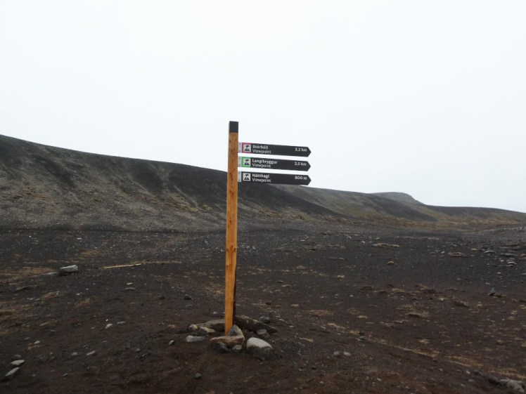 A signpost in Fagradalsfjall, pointing out various places of interest relating to the 2021 eruption. The post seems to be untreated wood but the pointing fingers are professionally made.