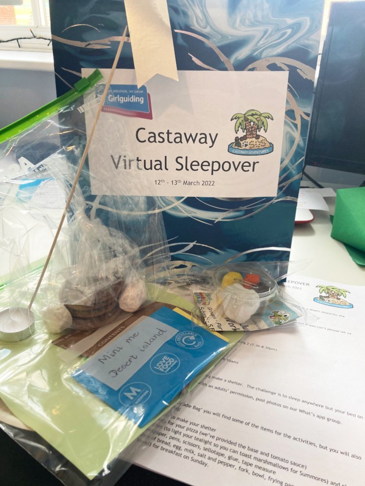 My Castaway virtual sleepover goodie bag: a blue marbled bag with a big label containing the theme and date. Scattered around it are my timetable, my smores bag and my craft bag.