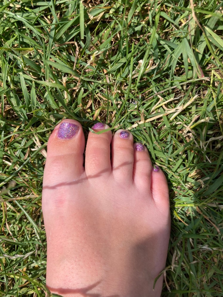 My foot in the grass. It has fairly distinct sandal tanlines by now and sparkly purple toes although you can't really get the holographic effect until you see them in motion - which I'm not sharing on the internet!
