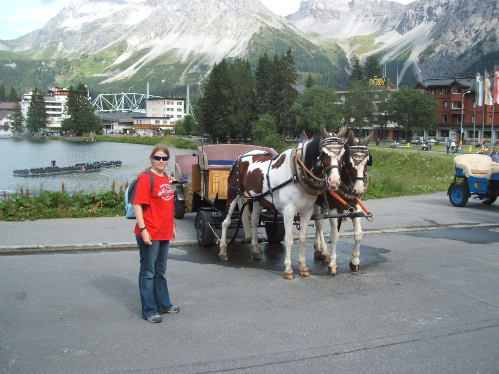 Me posing with a pair of brown and white horses harnessed to a simple cart by the lake at Arosa. I'm wearing a red t-shirt and bootleg jeans.