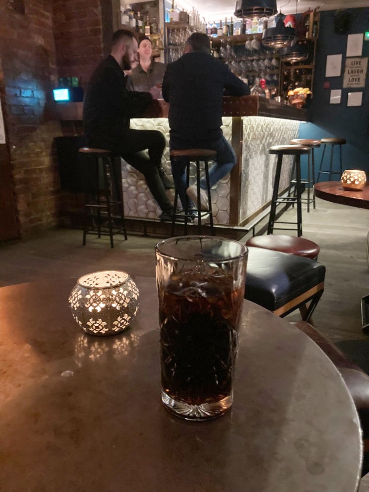 A decorative glass of Coke on a table in a dimly lit bar in Reykjavik.