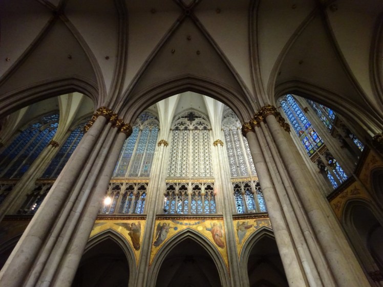 A view into the quire from the south ambulatory, seen through the pillars. Above the arches in the quire, there are frescoes of angels on very gold backgrounds and above, there's a row of huge windows with the subtle coloured patterns similar to the one I showed earlier.