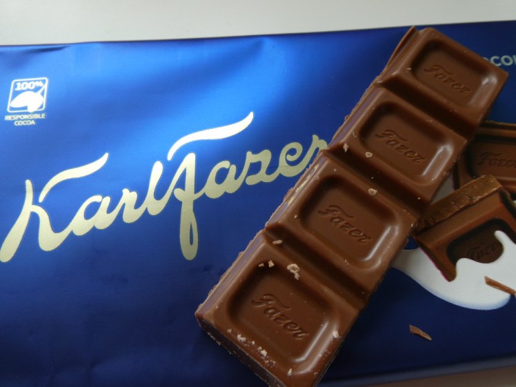 A strip of Karl Fazer chocolate lying on top of its semi-matt dark blue package.
