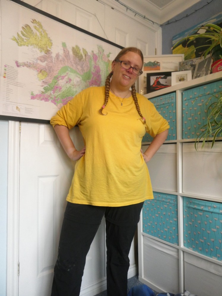 Wearing a thin long-sleeved t-shirt in a shade of yellow brighter and more canary-like than the slightly mustard yellow of the jumper earlier.