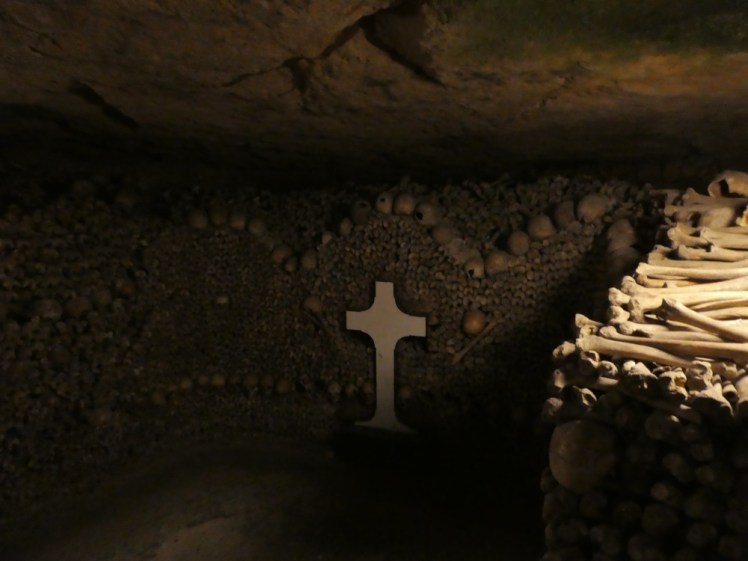 More bays of bones supported by thigh bones and lines of skulls. In the middle of the "wall" in this one is set a stone cross.