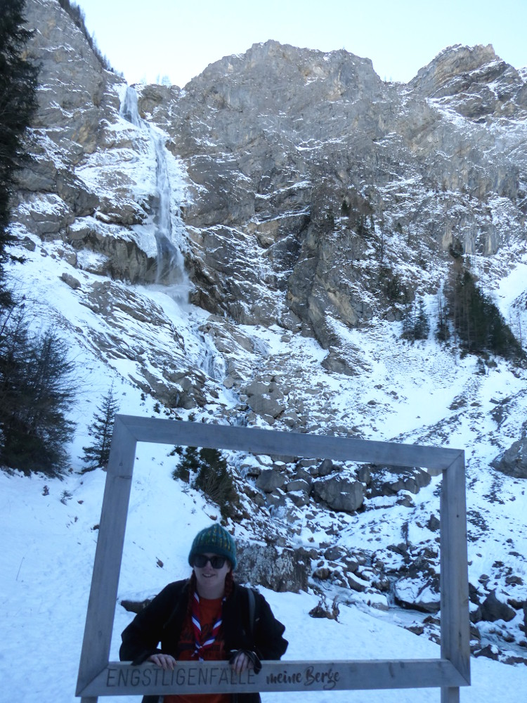 Me in a picture frame at the foot of the Engstligenfalle waterfall in Switzerland in the snow. I'm wearing a woolly hat, a heated jacket and my international neckerchief.