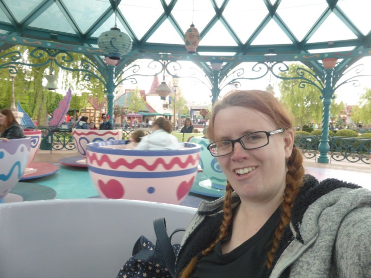 A selfie in the teacup ride at Disneyland Paris. It's a really bad picture. I'm wearing a black t-shirt under a grey hoodie lined with black fleece. It's warm but it's not exactly Disney.