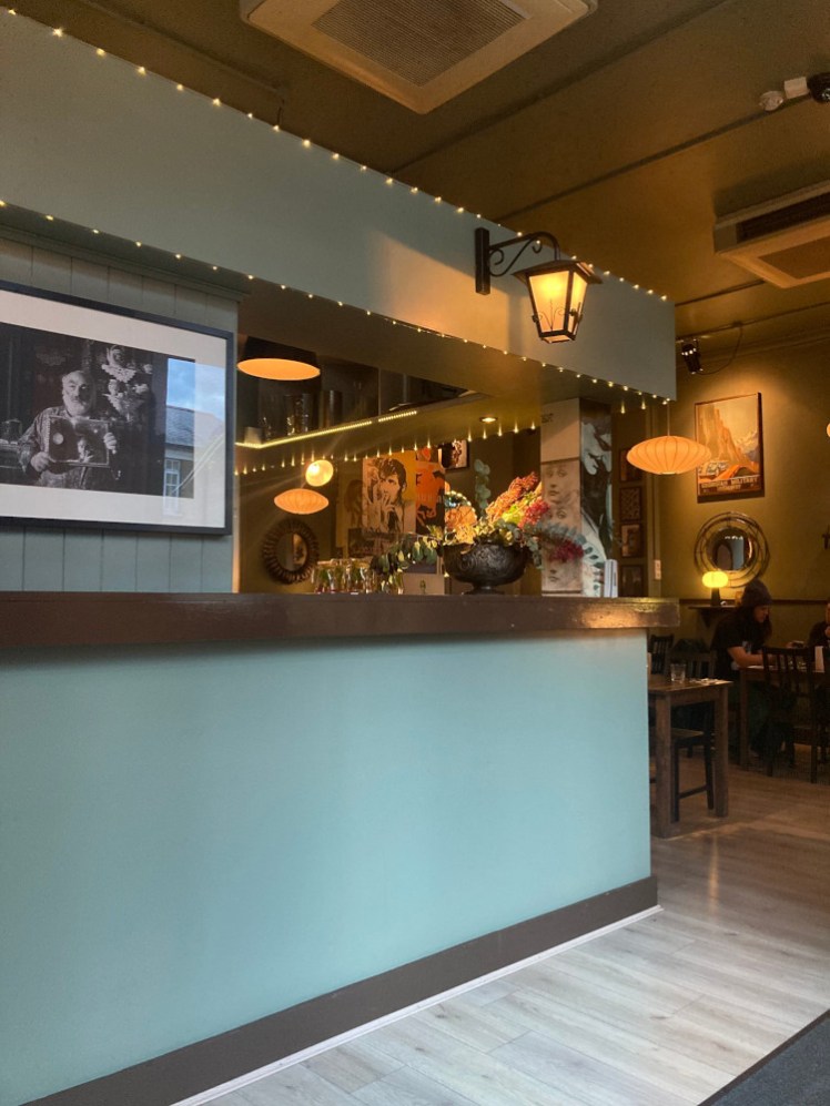 Inside Little Georgia. Most of the picture is the light mint-green bar, which has a lantern hanging from the middle of it and a string of LED ropelights around it but behind that, you can see the main seating area, where there are lots of lamps and lots of pictures. The whole effect is quite cosy.