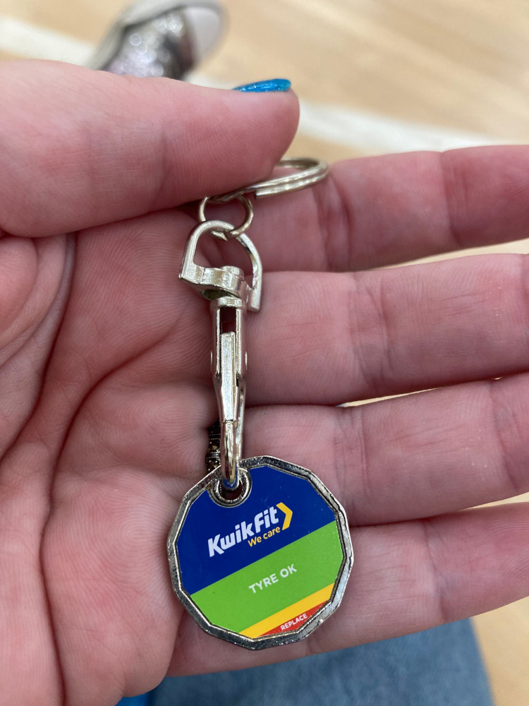 A 12-sided token on a clip on a keyring. The token is divided into a blue zone at the top (with the Kwik Fit logo), then a green, yellow and red zone to show where your tyres are and are not an ok depth.