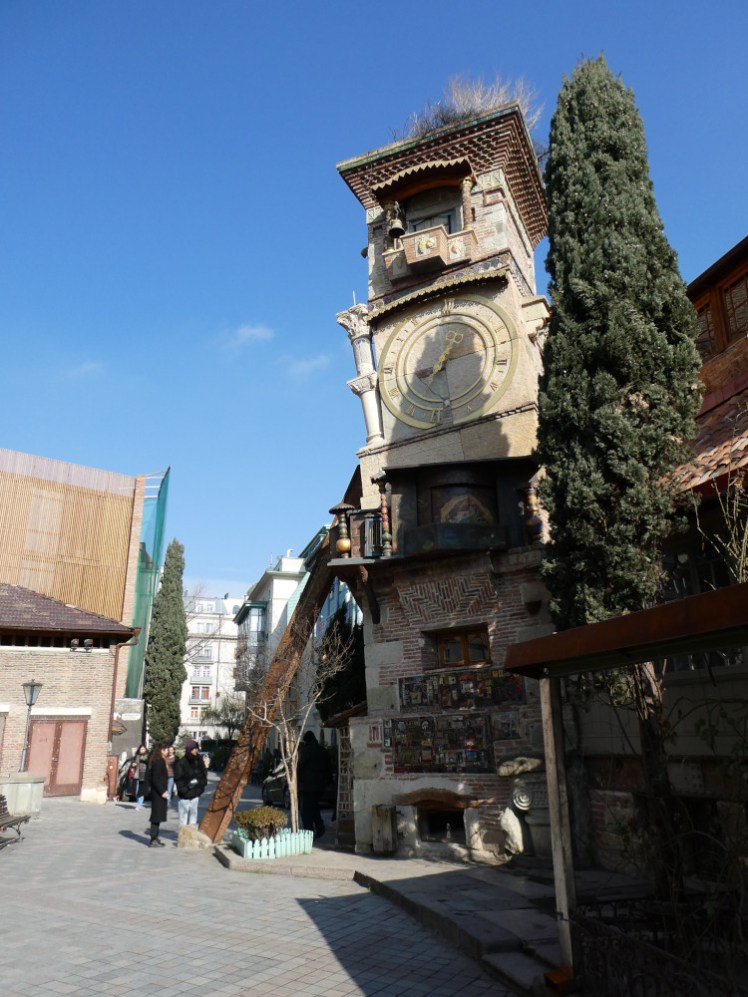 A leaning clock tower that looks like it's been made out of a dozen different buildings.