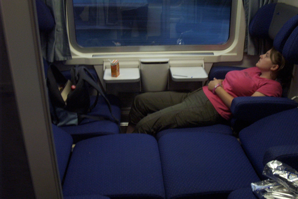 Jemma on the train on the way home. It's dark outside the window. The seats in the compartment have been pulled out to make something bed-like. It's not a sleeper train, it's an ordinary train just running later in the evening.