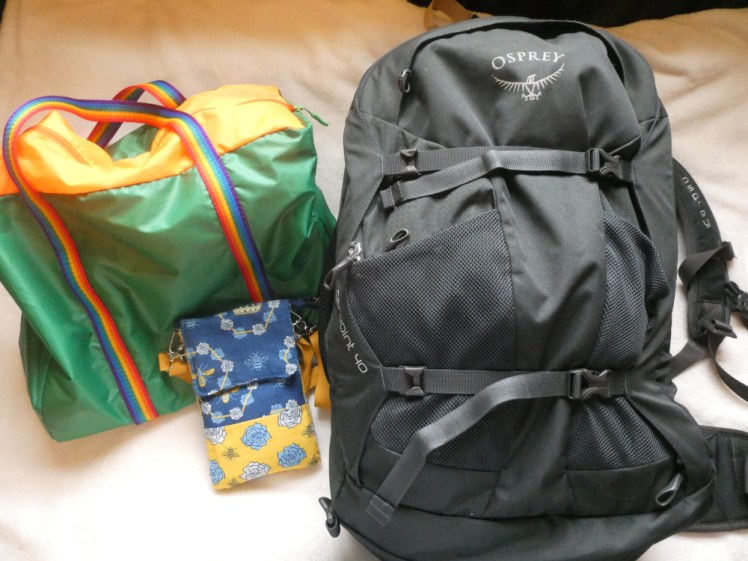 My luggage - a black Osprey Farpoint 40 which is slimmer than it's ever been when I've packed it before, and a green tote bag with an orange zipped top and rainbow-striped straps. At the front is a tiny passport-sized bag in blue and yellow fabric with bee motifs on.