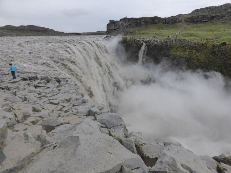 Dettifoss as seen from the east bank, an absolute storm of water and spray. You can't tell where the shattered grey east bank actually ends and the water begins. On the other side, the ground is noticeably smoother and greener.