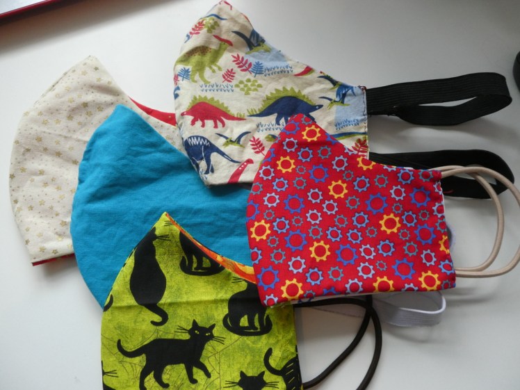 My fun fabric mask collection side 2: plain but bright blue, gold stars, black cats, gears & dinosaurs