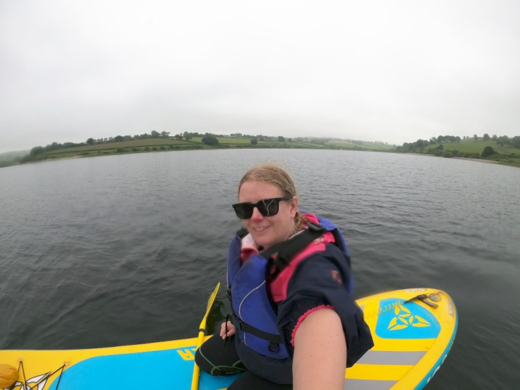 Me on my paddleboard, wearing a purple buoyancy aid and looking a little bedraggled, in the middle of the lake.