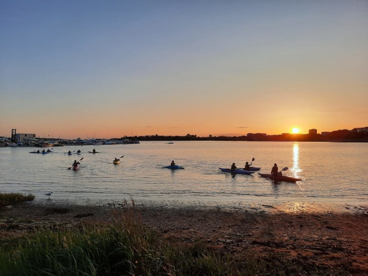 My Guides returning from sea, silhouetted against an orange sunset.