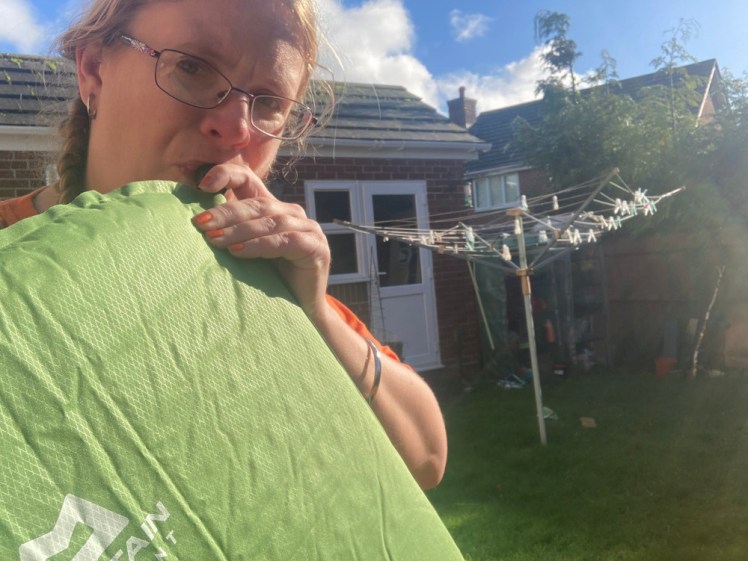 Me, blowing up my so-called self-inflating mat. The corners of my orange t-shirt poking out around the green mat clash quite badly.