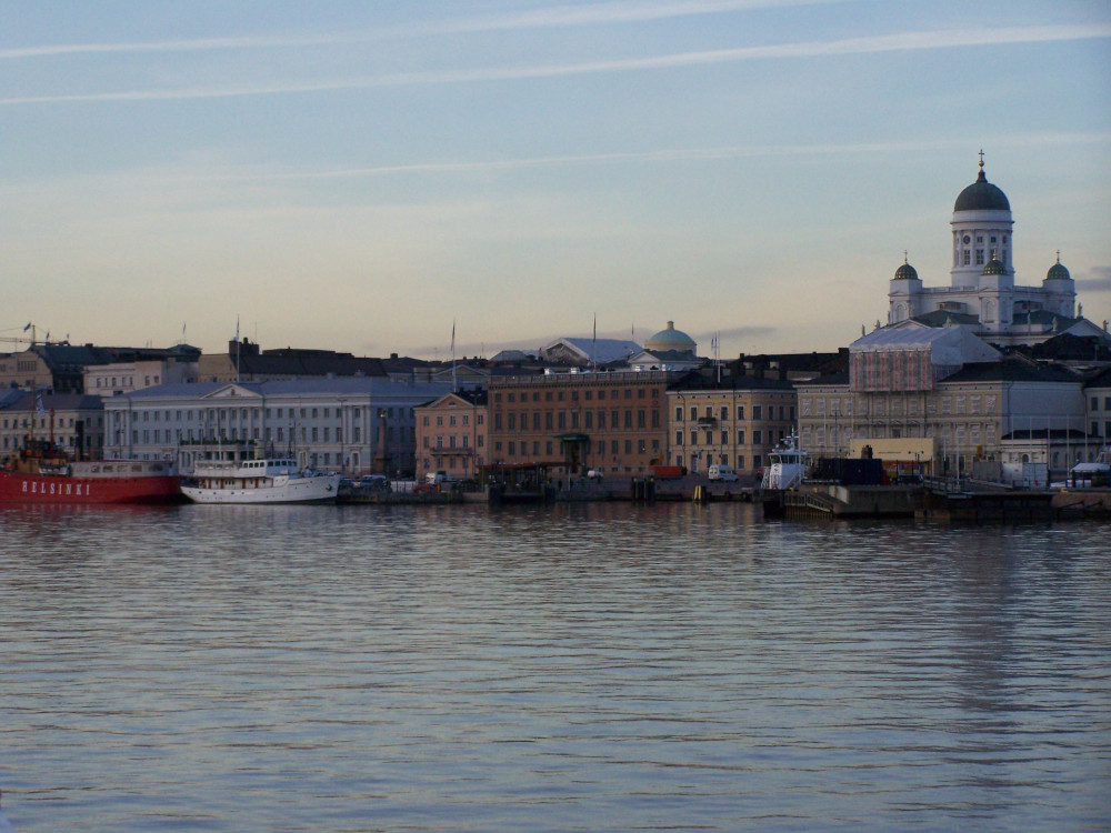 Helsinki seafront. A late winter afternoon. The sky is pastel blue with a hint of yellow lower down, the buildings are colourful and a square white cathedal dominates the skyline.