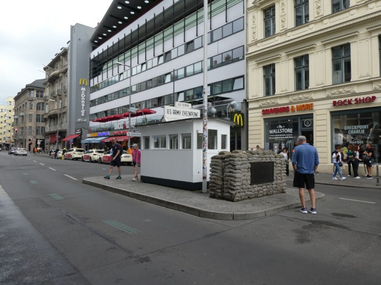 Checkpoint Charlie, a small white hut in the middle of the road with a sandbank wall in front of it. Most of the tourists visible in this picture are on the far side of the road but in just a couple of minutes, they'd be swarming across the road oblivious to cars.