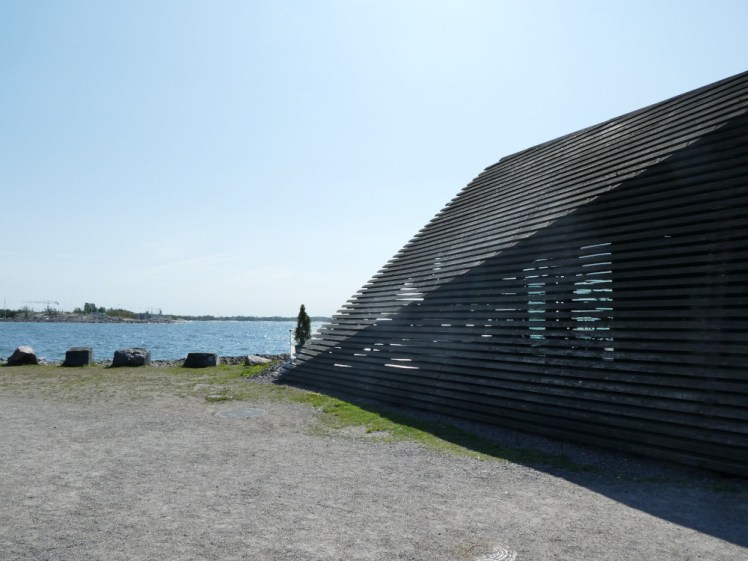 The side of the building, showing how you can see between the wooden slats.