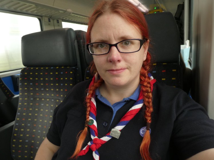 A selfie in my navy Girlguiding polo shirt and striped international neckerchief. I'm on a train on my way across Switzerland for a week at world centre Our Chalet.