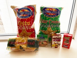 Two packs of star-shaped crisps. The red packet contains cheese flavour and the green packet contains sour cream flavour. There's also a packet of hamburger rolls, plastic cheese, a carton of chocolate milk and a carton of strawberry juice. These ones are sitting on the windowsill of my apartment in Reykjavik.