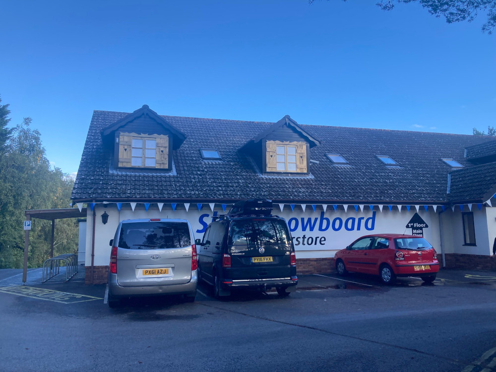 A long building with a chalet-style roof. Gable windows are poking out and they have pine alpine-style shutters over them.
