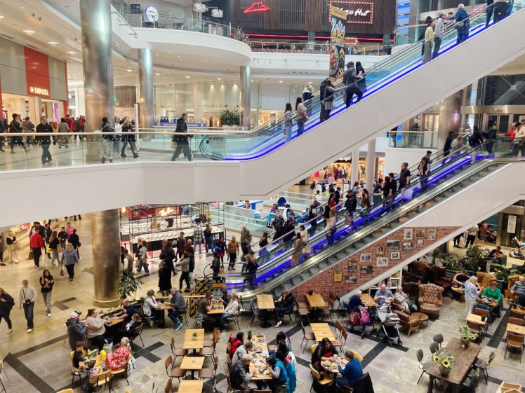 Inside Westquay Shopping Centre - three levels with escalators between them and lots of people on the floors and the escalators.