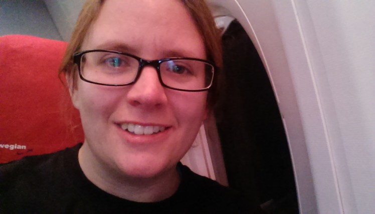 Selfie on a plane. The light levels are clearly low enough that my camera was struggling because it's kind of grainy. You can just make out from the seat back behind me that this is a Norwegian plane.