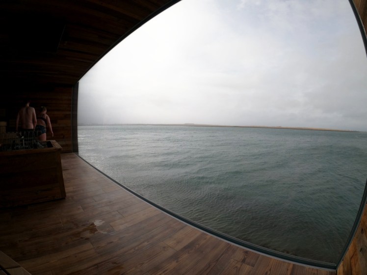 The sauna's big window open onto a greyish-blue sea and a heavy grey sky. It must be spectacular on a nice day.