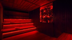 Lava Sauna: a dark sauna lit in red lights. The wooden benches glow red, as does the wall decoration, lots of red, black and transparent rocks behind a pane of glass.