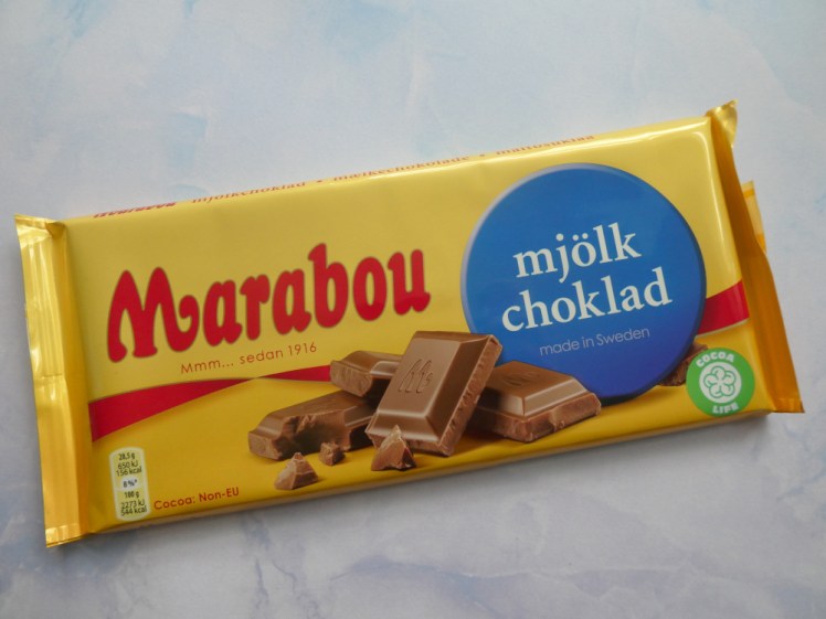 A 200g bar of chocolate in yellow flow wrap. It has its name, Marabou, in decorative red letters on the left and a blue bubble declaring "milk chocolate" in Swedish taking up most of the right-hand side. Underneath and between the two is a picture of a pile of chocolate chunks.