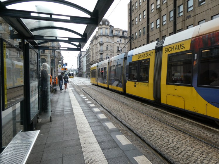 A yellow Berlin tram on the opposite tracks to the platform I'm standing on.